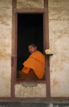 Portrait of Therevaden Buddhist monk framed in window of building.
