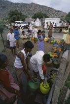 People queuing with their plastic water pots to collect water from the common village tap.Stand pipe colourful pots Colorful