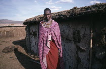 Masai woman standing outside traditional mud dwelling near the Masai Mara.