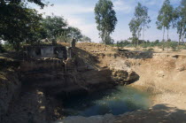 Open dug well with electric pump irrigating dry area