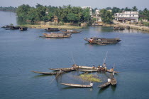 Fishermen on boats with a net cast around reeds in the river