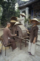 Monks husking rice in a traditional hand driven machine