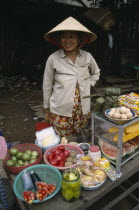 Smiling woman wearing traditional conical hat selling fruit and vegetables beside the roadHo Chi Minh City