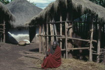 Tutsi man sitting outside his home and cattle pen.