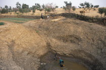 View of deep waterhole and onion fields with farmers working. Tereli