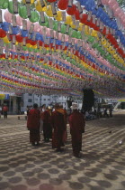 Jogyesa Temple.  Canopy of paper lanterns and prayer streamers hung to celebrate the birthday of Buddha with group of Tibetan Buddhist monks standing below.