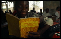 Mwenge Primary School child reading a text book in the classroom.