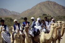Nomads riding camels on road between keren and Agordat with backdrop of hills.