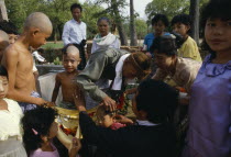 Young boys having their heads shaved during novice monk initiation ceremony.Burma Myanmar
