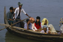 Man scissor rowing wooden canoe with passengers.Burma Myanmar