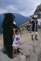Tourists crowd onto Chipsonbong summit  child posing with stuffed bear.