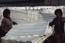 Women stacking sheets of hand-made mulberry paper used for door and window screens