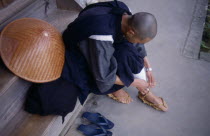 Bukokuji Monastery with Zen Buddhist monk tying up thong sandal made of rope.Zen Collection