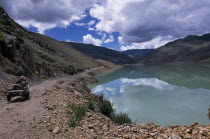 China, Tibet, Shigatse, Man-made dam with horse drawn cart on dusty road running alongside.