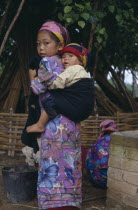 Dai girl carrying child on her back.