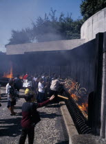 Pilgrims throwing candle offerings into fire