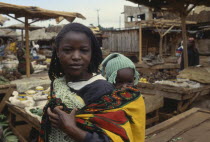 Young woman carrying her baby on her back in a colourful sling.