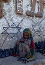 Smiling young girl crouched beside typically decorated house and traditional pottery.