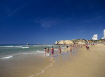 View along beach with people walking along the waters edge