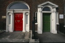 Two Georgian front doors  one red and one green  separated by railings. Both with white columns and arches.EireEireEireEireEire