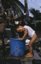 Young boy taking shower under water pump .