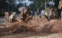 Men and women stone breaking with bricks and hammers