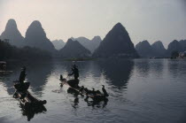 Cormorant fishermen on stretch of river in the Guilin area with limestone peaks behind.