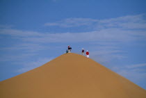 Tourists standing on top of Saharan sand dune.