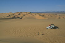 Tourists with four by four vehicles in desert landscape.