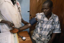 Man in refugee camp for Sierra Leonean  refugees having his blood pressure taken in the camp clinic.