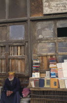 Arab book vendor beside street stall.