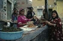 Young woman stall holder selling prepared foods at market.