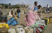 Women and children waiting at water point in provincial town.