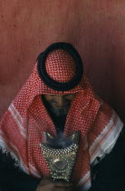 Portrait of Bedouin man inside tent looking down at studded leather artefact.