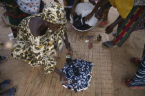 Women applying indigo dye to cloth during tie dye process.