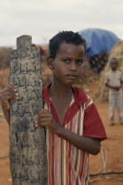 Somali refugee camp run by UNHCR.  Young boy attending Koranic school holding piece of wood inscribed with Koranic script. Moslem United Nations High Commissioner for Refugees