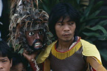 Man taking part in re-enactment of the crucifixtion during Easter week  head and shoulders portrait holding mask with feather head-dress.Holy Week