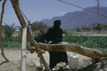 Tuareg filling water bottle at well. toureg