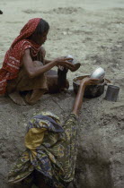 Women filling water vessels at well.