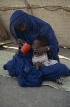 Mother helping her malnourished child to drink at Sinkat feeding centre. Center