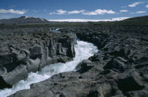 River crossing lava field with Langjokull ice cap in the distance