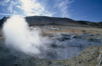 Hverir. High temperature geothermal area. Steam rising from the hot springs with visitors on the ground and mountains in the distance.The Hot Springs deposit it chemical sulphur which was collected t...