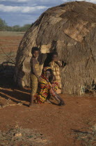 Woman and her two daughters outside their hut.