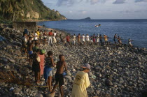 Villagers on beach pulling a seine net as fishermen attempt to catch tuna close to shore.