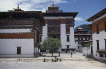 Tashicho Dzong courtyard with traditional architecture and small group of women and children in middle foreground.