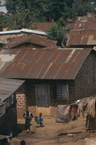 Kamwoyke slum area.  Woman and child outside brick hut with corrugated iron roof.