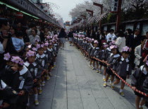 Nursery school children dressed for the flower festival on Buddhas birthday standing in line at the Senso Ji Temple Kannon temple.