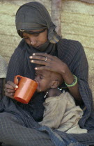 Mother feeding child at Sinkat feeding centre for malnourished children run by the Red Cross and Red Crescent. Center