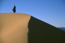 Tuareg man standing on ridge of sand dune.Nomadic muslims of Berber origin  toureg  Nomadic muslims of Berber origin  toureg
