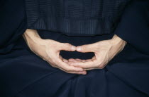 Cropped view of monk in Zen Buddhist monastery showing hands in Mudra the position of meditation